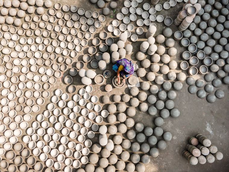 Hundreds of clay pots drying in the sun around a potter
